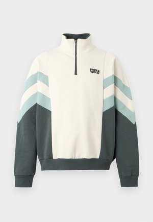 Sweat-shirt à demi-fermeture éclair avec partie supérieure blanche, manches inférieures et ourlet vert foncé, rayures chevron bleu clair et blanc sur les manches, et petit logo noir.