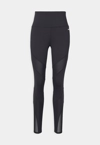 Zwarte sportleggingen met een hoge tailleband, voorzien van textuurlagen en mesh-inzetten voor verbeterde ademend vermogen en ontwerpdetails.