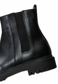 Bottines en cuir noir avec une finition texturée, des panneaux élastiques sur les côtés et une semelle en caoutchouc durable avec des motifs striés pour une adhérence optimale.