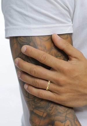 Hand mit einem goldenen gedrehten Ring, der auf einem tätowierten Unterarm ruht, Person trägt ein weißes Kurzarmhemd.