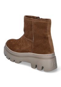 Botas de tobillo de ante marrón con una suela de plataforma beige gruesa, que destacan por su textura suave y un diseño de punta redondeada. Detalle de cremallera en la parte trasera.