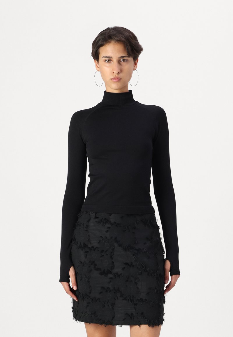 Black turtleneck top in a fitted design, paired with a black skirt featuring textured floral patterns and fringed accents.