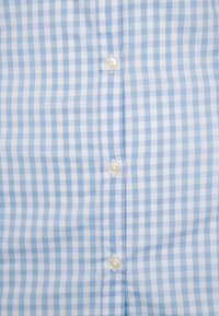 Blå och vit rutig skjorta i gingham, med knäppning fram med plastknappar, tillverkad av lätt och texturerad bomull.