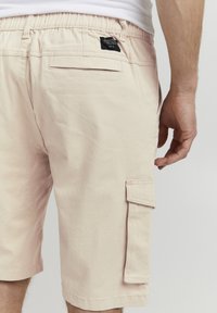 Shorts cargo roses en coton, dotés d'une poche latérale, d'une taille élastique et d'une poche arrière avec un détail en étiquette noire.