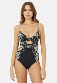 Zwarte badpak met witte bloemenprint, uitgesneden ontwerp bij de taille en verstelbare bandjes. Zachte stof met een gladde textuur.