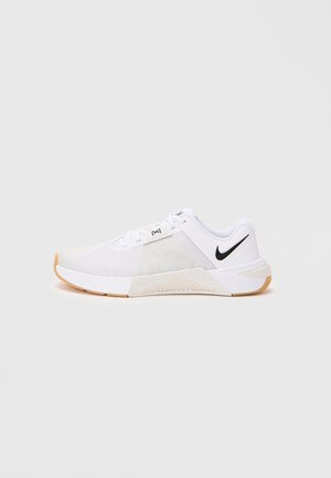 Hvide Nike herre sportsko med sort swoosh-logo, mesh-overdel og gummifarvet sål, vist fra siden på en hvid baggrund.