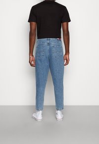 Ljusblå denimjeans med hög midja och tapered ben, med två bakfickor och en liten logotags vid midjan.