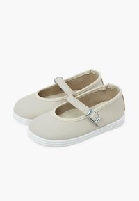 Zapatos Mary Jane de color beige claro, hechos de material sintético suave, con punta redonda, correa ajustable con hebilla y suela de goma blanca.