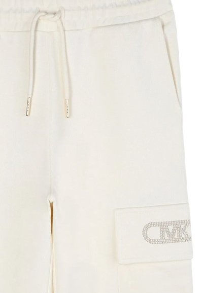 Kremowe dresowe spodnie z elastycznym pasem na sznurki, ribbowymi mankietami i wyraźną łatą z logo w cyrkoniach na bocznej kieszeni.