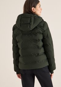 Giacca puffer verde oliva con cappuccio, caratterizzata da sezioni verticali trapuntate orizzontali e polsini elasticizzati. Texture liscia, design caldo e isolato.