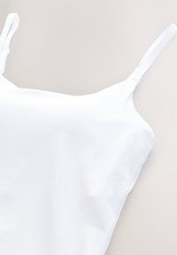 Top bianco senza maniche con spalline sottili, realizzato in tessuto liscio. Presenta un design aderente e dettagli di cucitura minimi. Il bordo è ben rifinito.