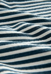 Tejido a rayas en azul y blanco con una textura suave, que presenta rayas alternas estrechas y anchas, mostrando suaves pliegues.