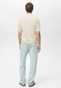 Light beige knit short-sleeve shirt paired with light blue wide-leg pants, featuring back pockets and a relaxed fit.