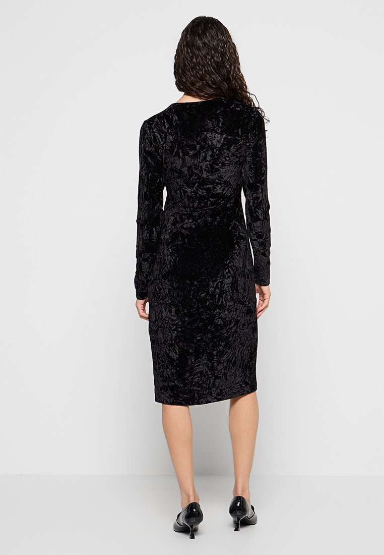 Schwarzes Samt-Midikleid mit langen Ärmeln, strukturiertem Stoff und figurnaher Silhouette, mit rundem Ausschnitt und knielanger Länge.