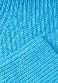 Tissu tricoté d'un bleu vif avec une texture côtelée, montrant deux sections superposées avec des motifs de points différents.