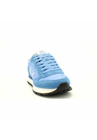 Sneaker azzurro chiaro con parte superiore in suede, lacci piatti e dettagli bianchi. Suola in gomma con motivo di battistrada testurizzato, con logo sul lato.