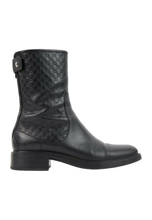 Botte mi-mollet en cuir noir avec motif embossé sur la partie supérieure, une bride latérale avec un bouton en métal, et un talon bas empilé.