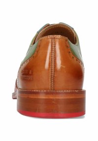 Braunes Leder-Schuh mit glatter Oberfläche, kontrastierenden grünen Akzenten und einer rot eingefassten Holzsohle. Verfügt über dekorative Perforationen.