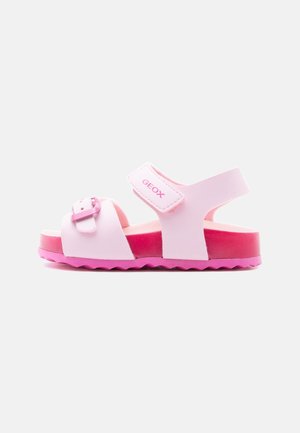 Sandalo rosa per bambini con fibbia regolabile e cinturino in velcro, suola scanalata e plantare imbottito, progettato per comfort e supporto.