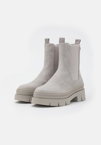 Pair of light gray suede Chelsea boots with chunky rubber soles and elastic side panels, shown against a white background.