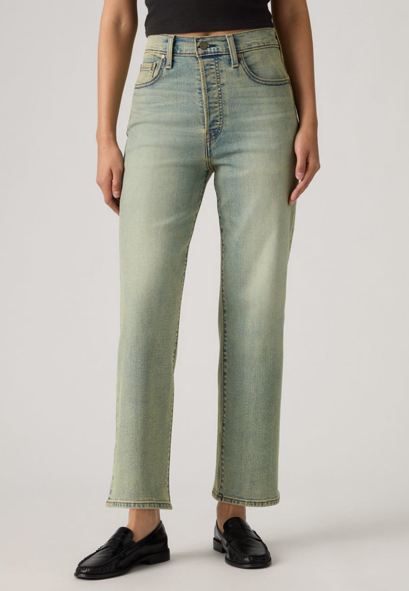 Ανοιχτό πράσινο τζιν με ψηλή μέση, κατασκευασμένο από denim, με ευθεία γραμμή στα πόδια, στυλ με πέντε τσέπες και διακριτική ξεθώριαση. Συνδυασμένο με μαύρα μοκασίνια.
