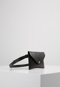Borsa a cintura in pelle nera con design a patta piegata, chiusura a scatto e tracolla regolabile per una vestibilità sicura. Texture liscia e stile minimalista.