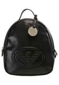 Sac à dos en cuir noir de forme arrondie, avec un logo en relief et un charm métallique sur la fermeture éclair. Il présente une surface texturée et une sangle ajustable.