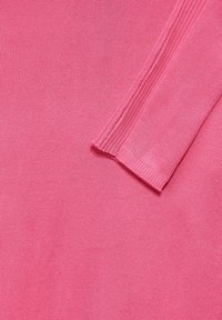 Rosa stickad tyg med en jämn textur och ribbade detaljer längs kanterna. Halvgennomsiktig, lätt och figurnära design.