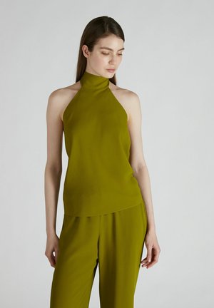 Top con collo halter in verde oliva realizzato in un tessuto liscio e leggero. Presenta un design aderente con un orlo allungato, abbinato a pantaloni coordinati.
