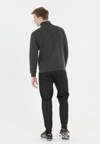 Grå pullover med høj krave og tekstureret stof, parret med sorte tapered joggers og sorte atletiske sko.