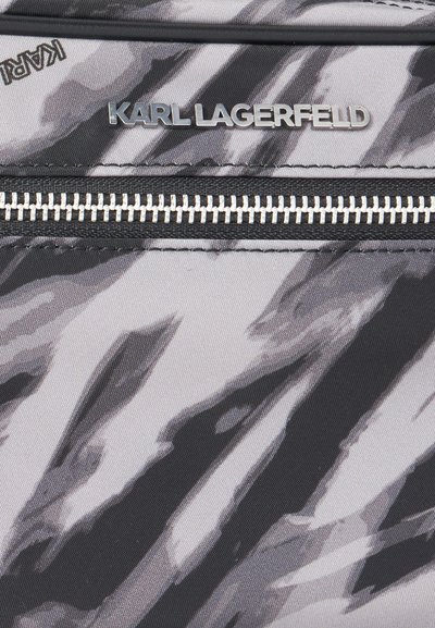Близък план на черна и сива чанта с шарка, със сребристо лого KARL LAGERFELD и хоризонтален цип.