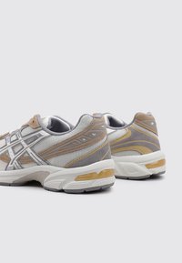 Zapatillas deportivas con parte superior de malla y ante en gris, beige y amarillo. Presentan acentos texturizados y una suela acolchada.