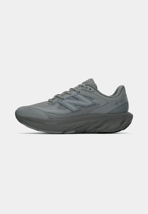 Grijze New Balance hardloopschoen met een gevoerde zool, bovenwerk van mesh en veters, van opzij weergegeven op een witte achtergrond.