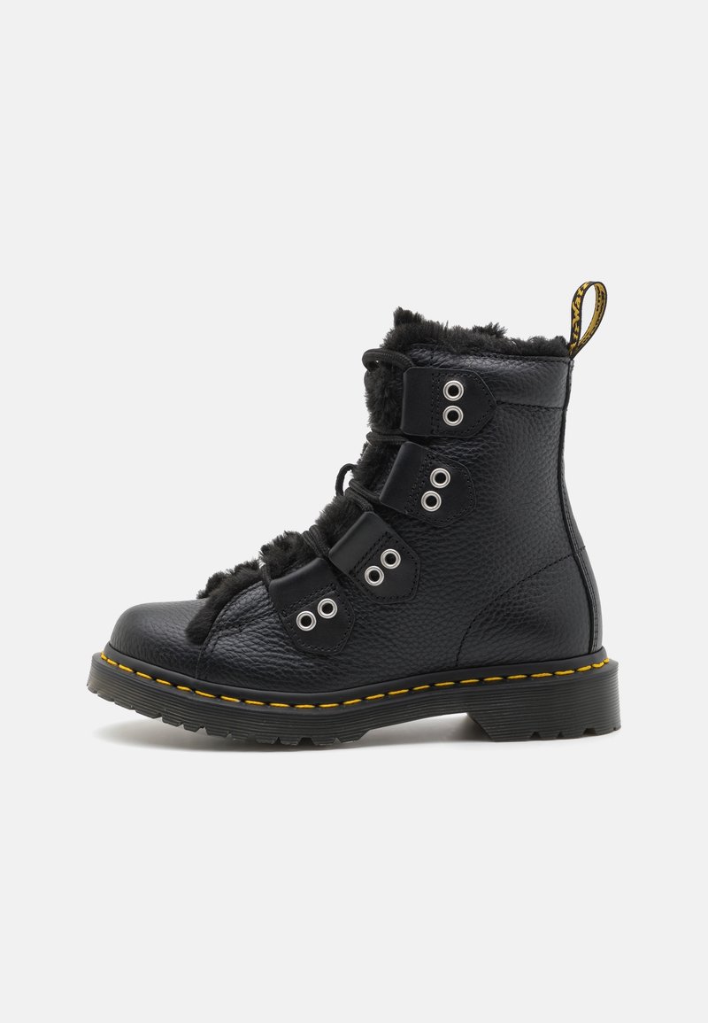 Botte d'hiver en cuir noir avec semelle en caoutchouc épaisse, coutures jaunes, trois sangles avec œillets métalliques et doublure en fourrure à l'intérieur et autour du haut.