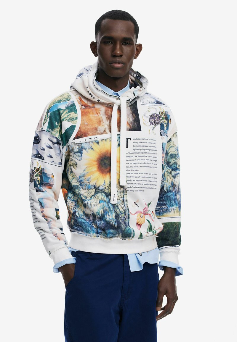 Hættebluse med et collage af farverige billeder og tekst, overvejende hvid med accenter i grøn, gul og blå.
