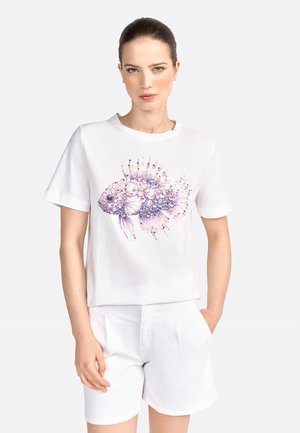 T-shirt en coton blanc à manches courtes avec un design de poisson coloré orné de pierres précieuses et d'éléments floraux, associé à un short blanc.