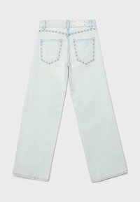 Jean droit en denim bleu clair avec poches arrière et détails en clous métalliques le long des bords des poches et de la ceinture.