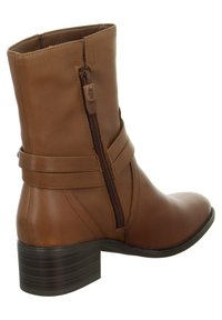 Bruine leren enkelboot met een zijrits, contrasterende stiksels, een ronde neushak en een gestapelde hak. Heeft een decoratieve riemdetails.