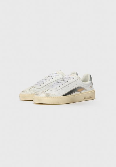 White sneakers with silver accents, textured detailing on the toe, and a slightly worn beige sole. Features lace-up closure and perforated design.