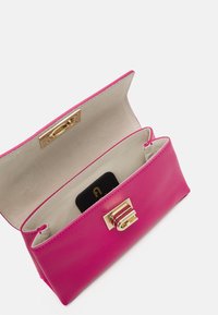 Růžová kožená kabelka s texturovaným povrchem, zlatým kováním a klopným zapínáním. Interiér je béžový s dvěma přihrádkami a přihrádkou na karty.