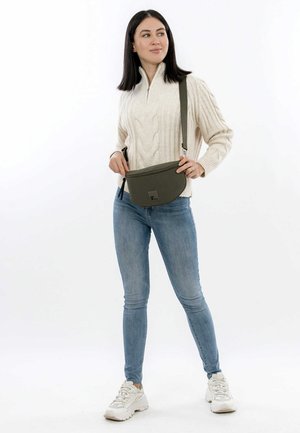 Alyvuogių žalios spalvos rankinė per petį, lygiu, matinio paviršiaus, suapvalintos formos ir mažo logotipo priekyje. Įtrauktas reguliuojamas dirželis.