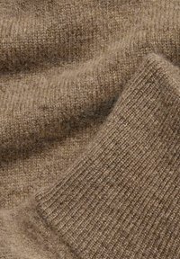 Brauner Wollstoff mit einer weichen, flauschigen Textur; zeigt ein geripptes Strickmuster und eine glatte Fläche, die unterschiedliche Brauntöne präsentiert.
