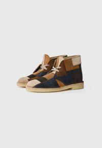 Brown and blue patchwork suede ankle boots with a rounded toe, white laces, and beige rubber soles. Features tan leather accents.