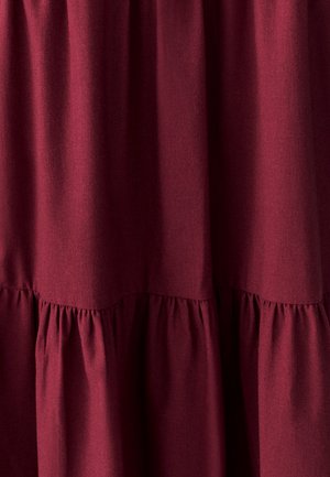 Tessuto bordeaux con una superficie liscia, caratterizzato da dettagli plissettati lungo l'orlo, che creano un design fluido e a strati.