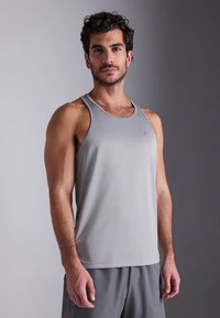 Szürke, kerek nyakú, könnyű anyagból készült trikó. Finom textúrával és a mellkason kis logóval rendelkezik.