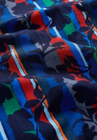 Bunt gemustertes Gewebe mit floralem Muster, das einen marineblauen Hintergrund, kräftige rote, grüne und blaue Streifen sowie eine strukturierte Webart aufweist.