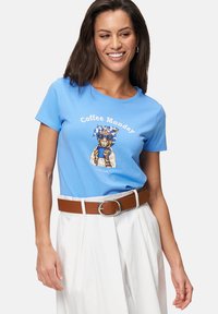 T-shirt en coton bleu avec un graphique d'un chat portant des lunettes de soleil et une écharpe, avec le texte "Coffee Monday" en blanc. Assorti à une ceinture marron.