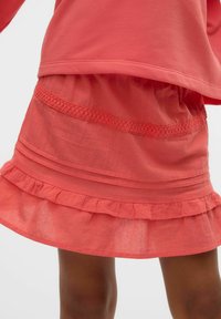 Koralfarvet lagdelt nederdel med volangkant og blonde detaljer. Fremstillet af et let, struktureret stof. Casual og lagdelt design.