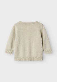 Helle beigefarbene Strickjacke mit Rundhalsausschnitt, Dreiviertelärmeln sowie gerippten Bündchen und Saum. Verfügt über einen glatten, strukturierten Stoff.