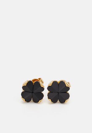 Boucles d'oreilles à clous noires en forme de trèfle à quatre feuilles, avec une finition polie et des accents dorés autour des bords.